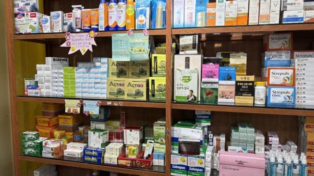 Shelves in a Hoi An pharmacy stocked with various medicines, skincare products, and health supplies.