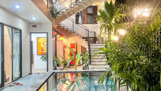 A modern Hoi An hotel with a pool, outdoor staircases, lush plants, and warm lighting at night.