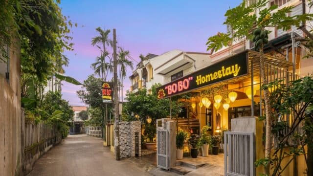 A homestay called BOBO with glowing lanterns on a quiet Hoi An street at sunset.
