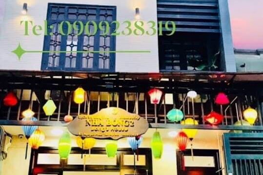 A brightly lit café in Hoi An with colorful lanterns hanging above the entrance and a motorbike parked outside.