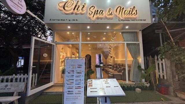 Chi Spa & Nails storefront at dusk in Hoi An, with illuminated sign and menu boards displayed outside.