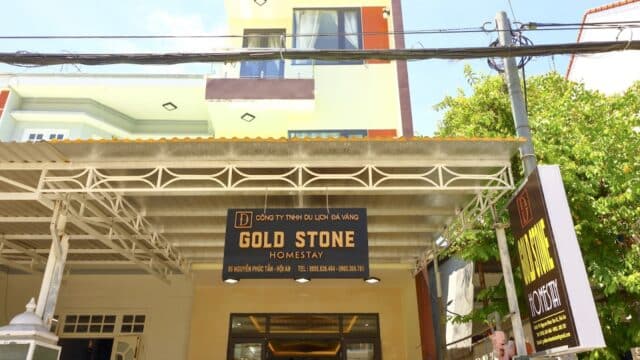 Front view of Gold Stone Homestay in Hoi An, featuring a sign above the entrance and a light green building behind.