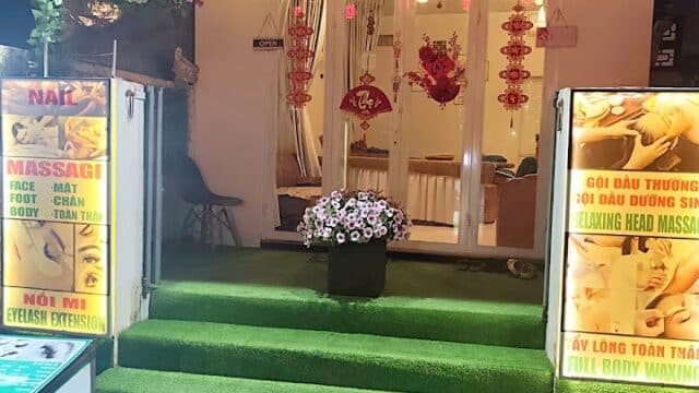 HaMee Spa entrance in Hoi An features green artificial grass steps, hanging flowers, and vibrant signs for massage and beauty services.
