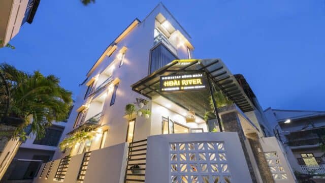 Modern three-story hotel building at dusk with illuminated Hoi An Hai River Hotel sign above entrance, offering a true Hoi An experience.