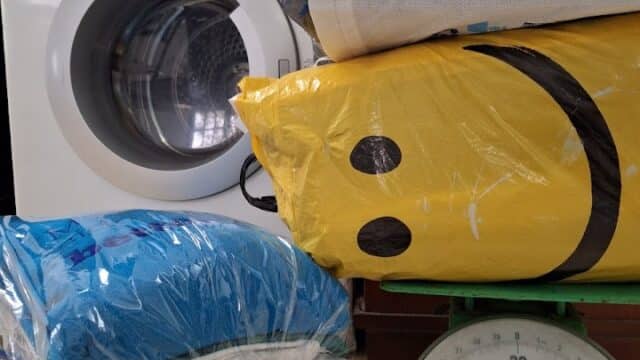 Bags of laundry and linens near a washing machine and weighing scale in Hoi An.