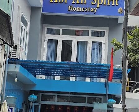 A three-story building in Hoi An, with a Spirit Homestay sign, bikes parked outside, and blue accents on the entrance.