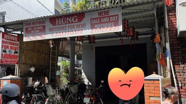 A motorbike rental shop in Hoi An with bikes parked outside, people nearby, and signs advertising motorbike services.