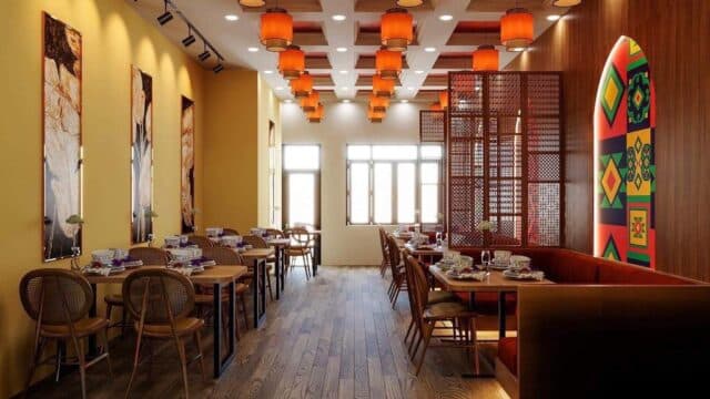 A brightly lit Hoi An restaurant with wooden tables, orange lanterns, and colorful geometric wall art on the right side.