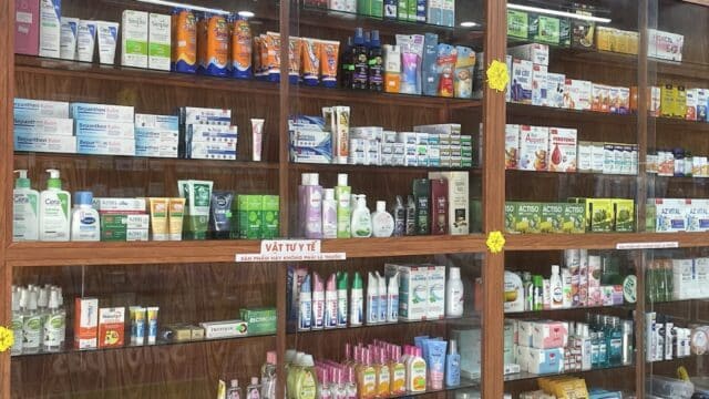 Shelves filled with various medicines, health products, and medical supplies in a Hoi An pharmacy display case.