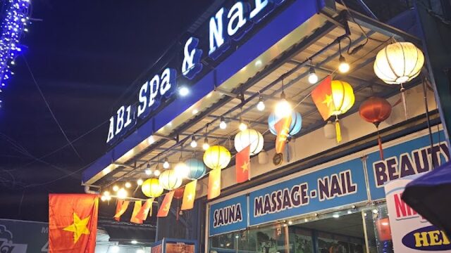 A spa and nail salon at night in Hoi An, glowing with lanterns, blue lights, and a Vietnamese flag by the welcoming entrance.