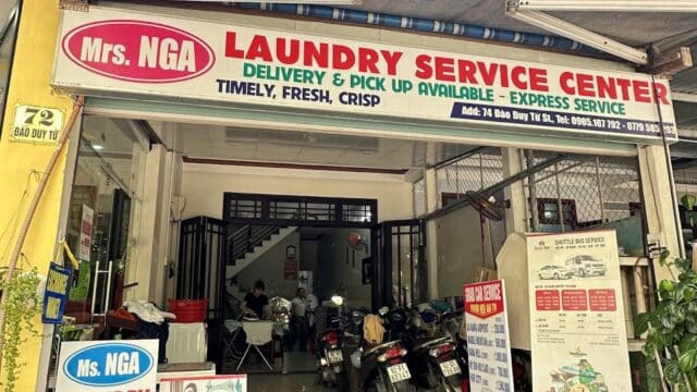 Front view of Mrs. NGA Laundry Service Center in Hoi An, with motorbikes parked inside and various service signs.