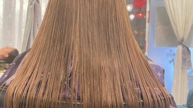 Person with straight, wet, light brown hair sits in a Hoi An salon chair, with stylish decor visible in the background.