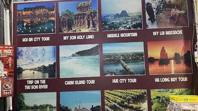 A wall with Vietnam tour posters and photos, including Hoi An, My Son Holy Land, and Ha Long Bay, above an office desk.