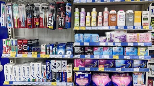Store shelves in Hoi An stocked with toiletries, including dental care, soaps, feminine hygiene, and skincare products.