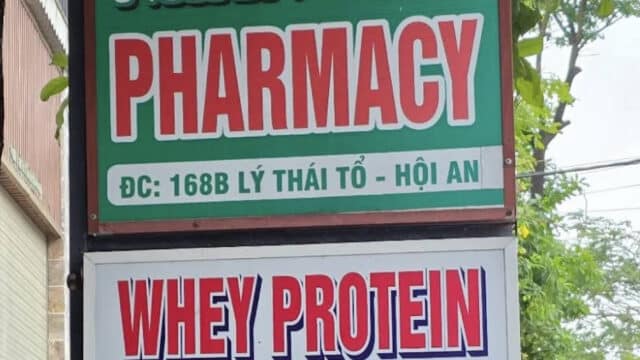 A pharmacy sign at 168B Ly Thai To, Hoi An, with a whey protein sign displayed right below it.