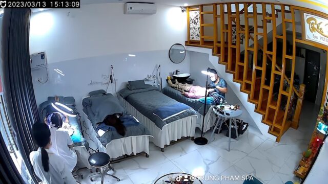 Three people enjoy spa treatments on beds in a bright Hoi An room with wooden stairs and a white tile floor.