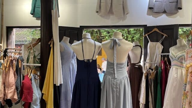Discover a Hoi An clothing store with dresses on mannequins, jackets on the wall, and racks of various garments.