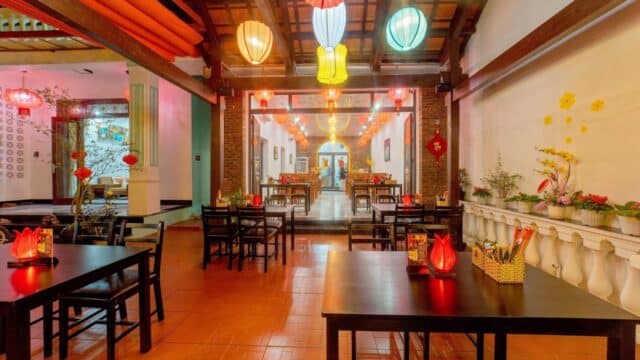Cozy Hoi An restaurant with lanterns, wooden tables, and warm lighting, featuring traditional Asian decor.