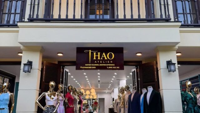 Storefront of Thao Atelier in Hoi An, featuring mannequins dressed in elegant formal gowns and suits at the entrance.