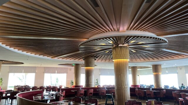 Spacious restaurant with Hoi An-inspired round wooden ceiling accents, red booths, large pillars, and abundant natural light.