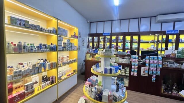 Interior of a well-lit pharmacy in Hoi An, with shelves and circular displays filled with various health and beauty products.