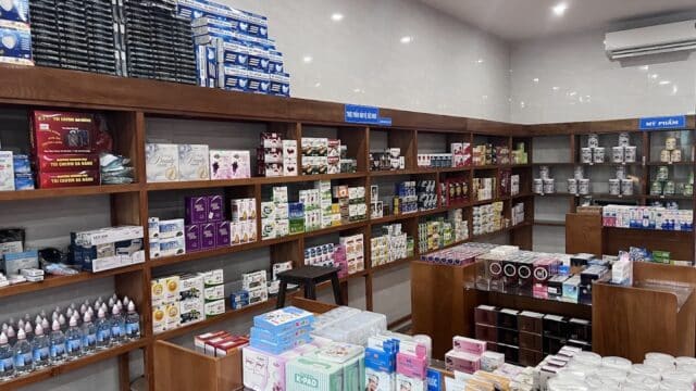 Pharmacy interior in Hoi An with medicine boxes, health products, and supplies neatly arranged on wooden shelves and glass counters.