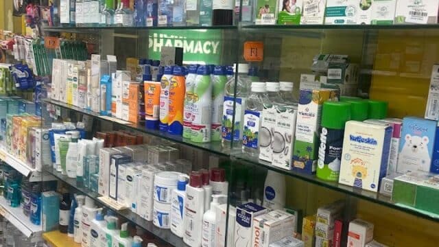 Shelves filled with various medicines, skincare, and hygiene products in a brightly lit pharmacy in Hoi An.