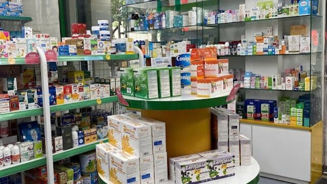 Pharmacy interior in Hoi An with shelves and medicine boxes; red flags with yellow stars are displayed above.