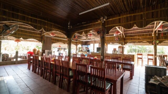 Open-air restaurant in Hoi An with wooden tables, a bamboo ceiling, and natural light streaming through large windows.