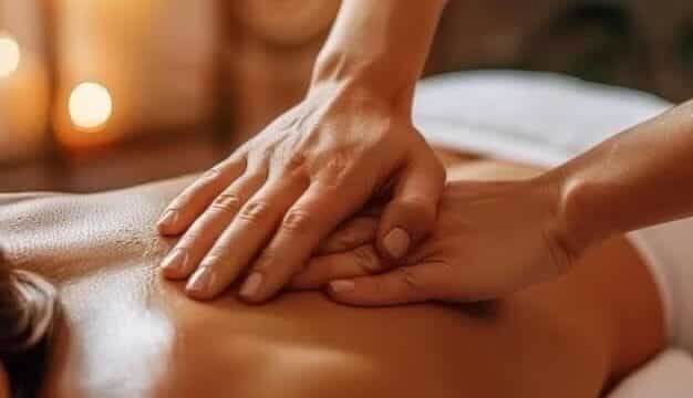 Hands giving a relaxing back massage in a spa setting with soft candlelight in the background in tranquil Hoi An.