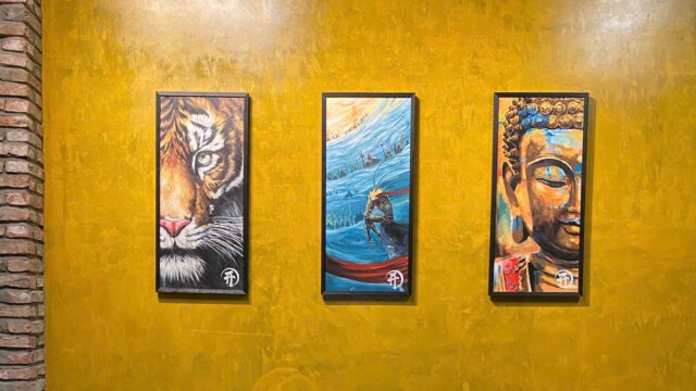 Tattoo Station Hoi An studio interior, framed Vietnamese-inspired paintings on a warm brick-and-ochre wall